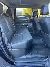 Load image into Gallery viewer, Interior view of a 2022-2024 Toyota Tundra CrewMax showing the under-seat storage with black upholstery